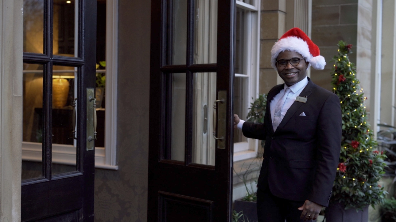 hotel work in a santas hat opening the door