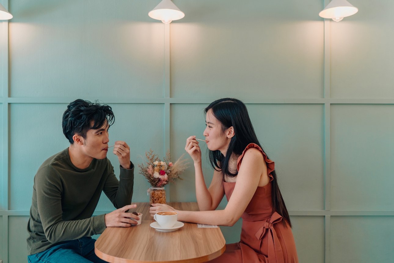 man and woman sat in cake shop sharing cake