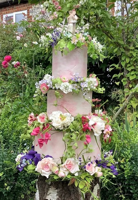 three tier pink cake deisgn covered in sugar flowers