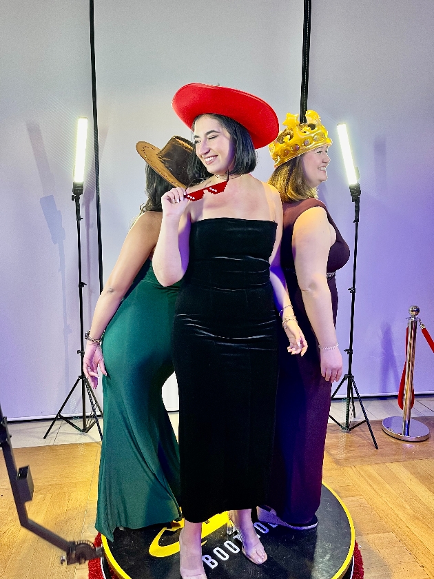 three guests wearing props on a turning stand