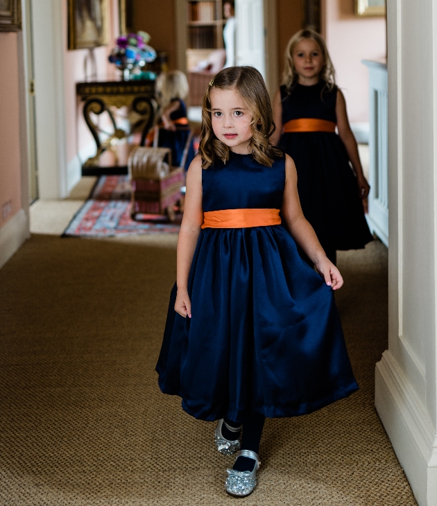 two flowergirl in navy dresses with orange sashes