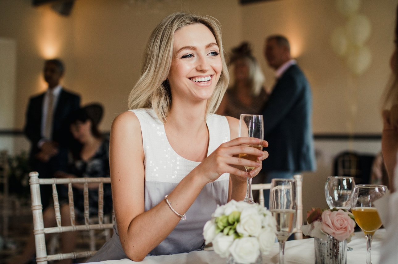 guest at wedding sat at table with a glass of fizz