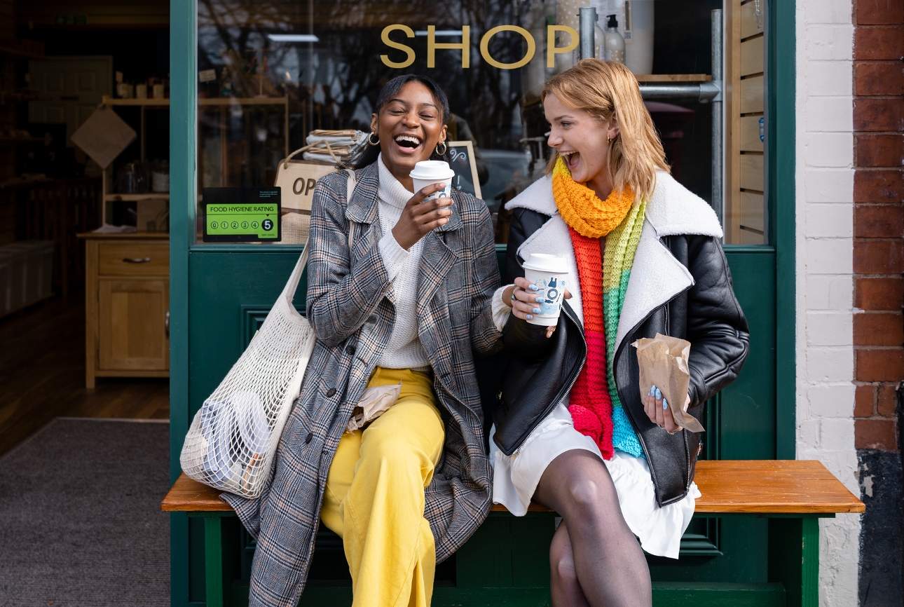 two people sat on a bench having a coffee