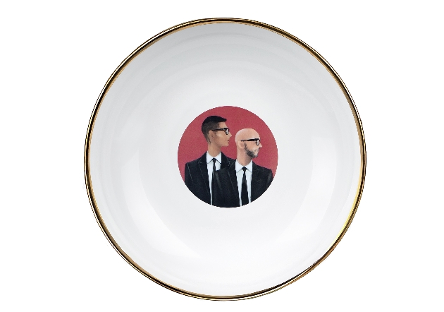 white pasta bowl with gold edge with two men in the centre