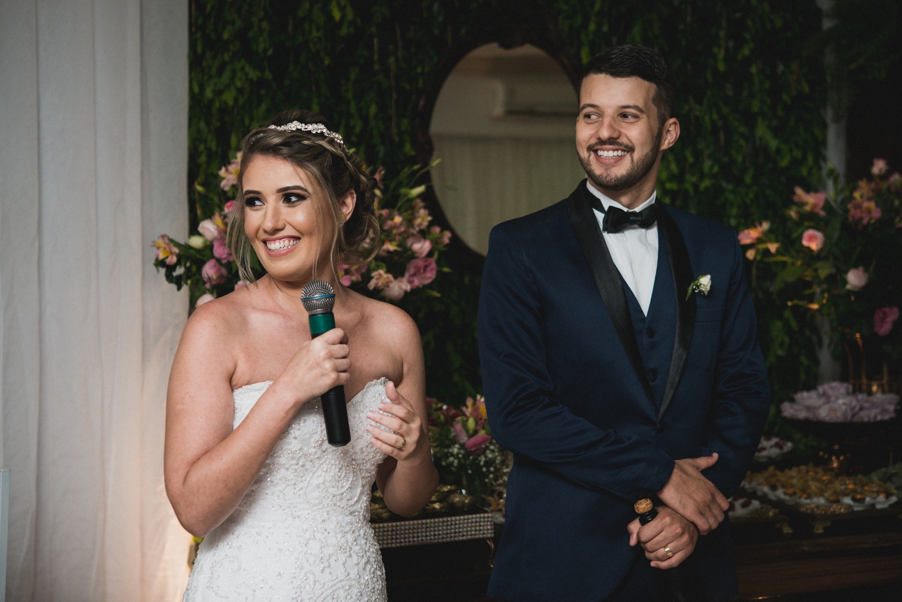 bride and groom standing together bride with mic giving a speech