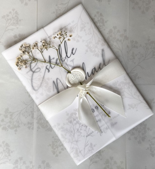 invite wrapped in bow with flower and wax seal