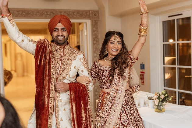 newlywed couple in indian wedding attire entering reception room