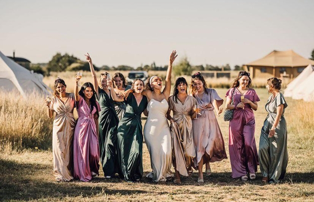 bride with friends in coloured dresses in field