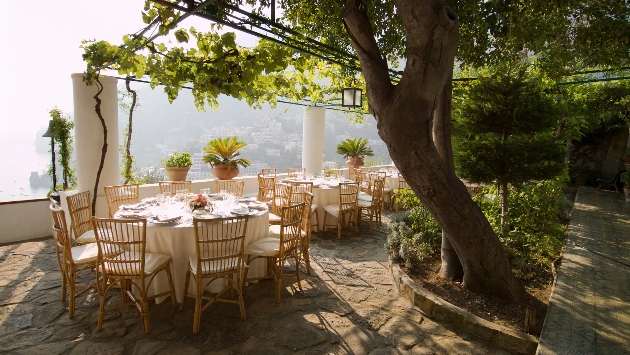 restaurant tables on terrace trees and vines covering it