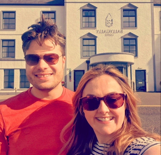 couple in sunglasses stood in front of hotel