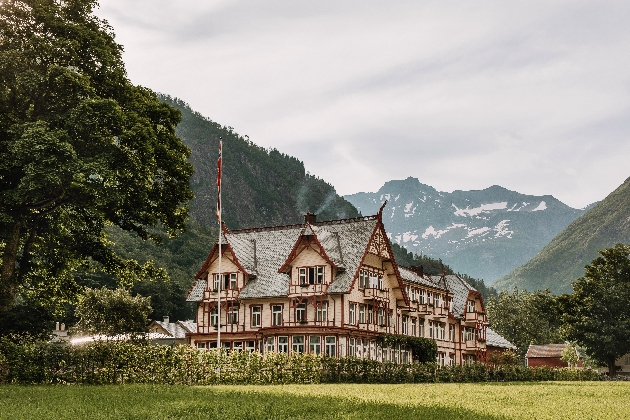 A grand hotel decorated in cream and red surrounded by beautiful countryside