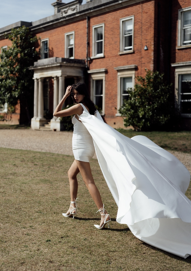 model in short white dress with attached cape full length 