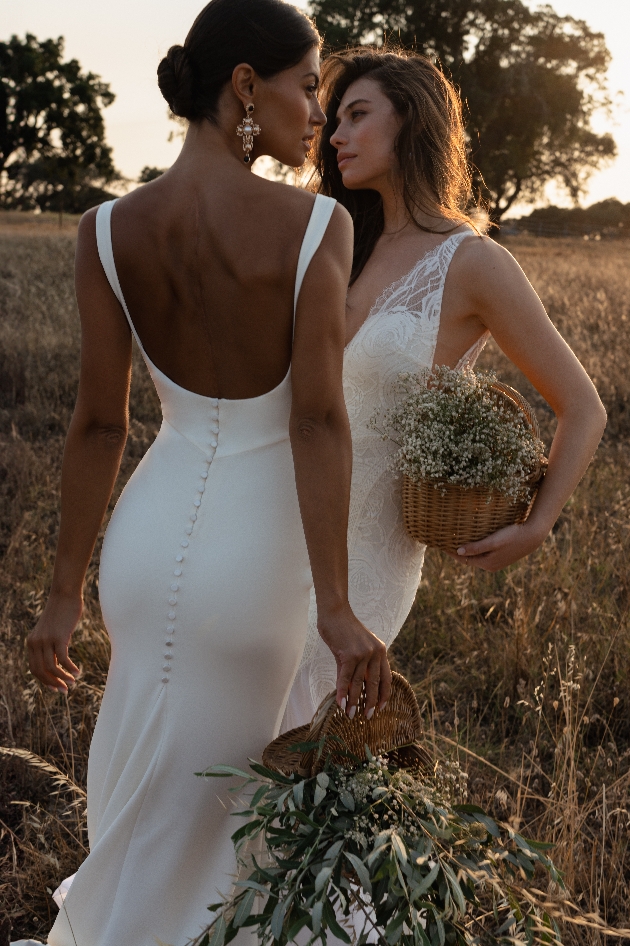 two models in wedding dresses in white slim fit fishstail dress with straps and low cut deep scoop back 