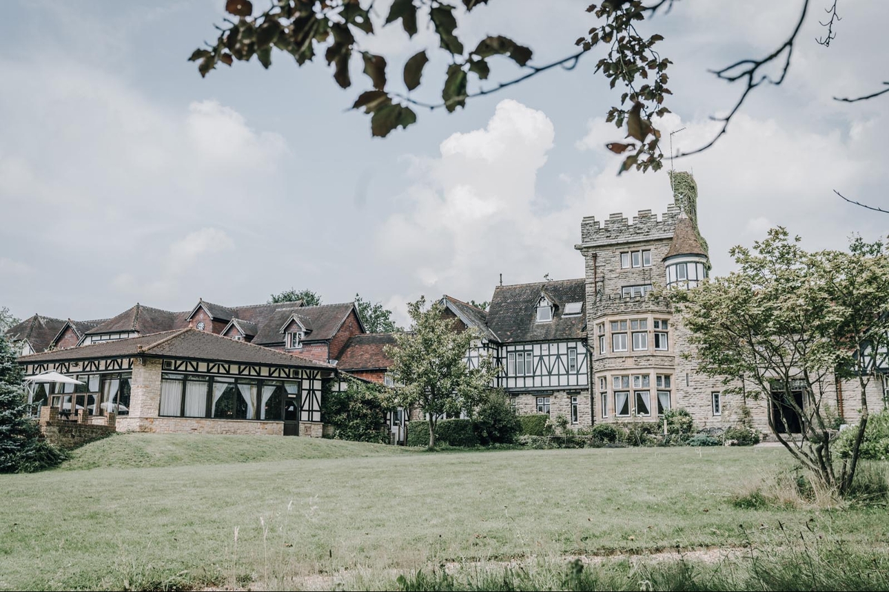 historic country house, with turret looking facade and conservatory attached over gardens