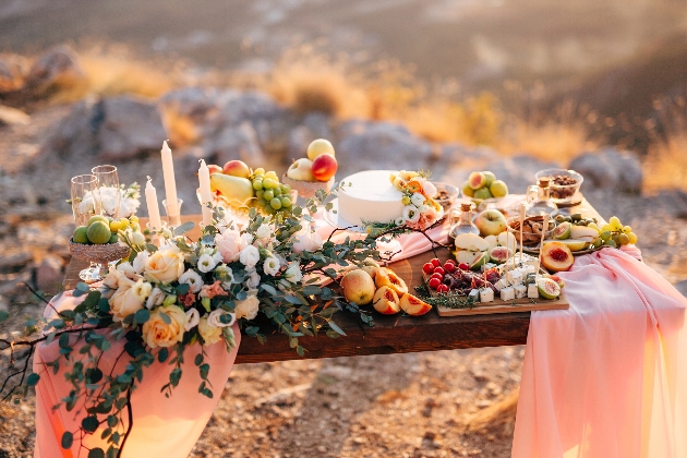 catering table with food and fruit with peach fabric drape