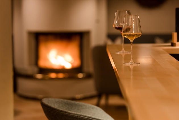 Two glasses of wine on a table with a fireplace in the background
