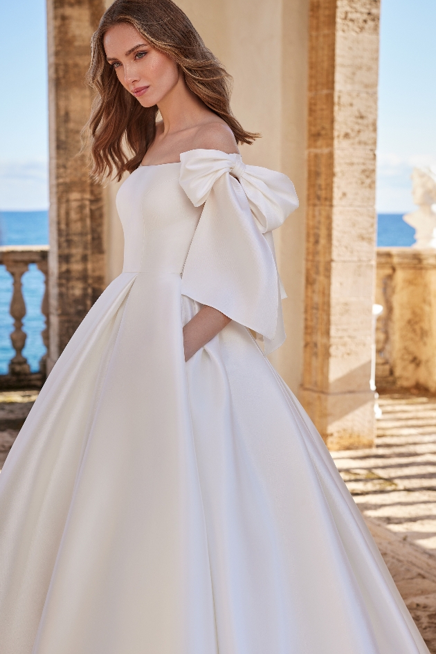 model in satin dress with bow details on sleeves