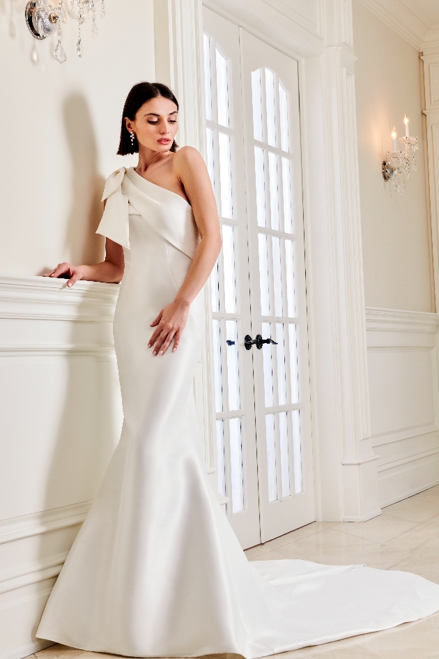 model in fishtail gown with one shoulder with bow shoulder
