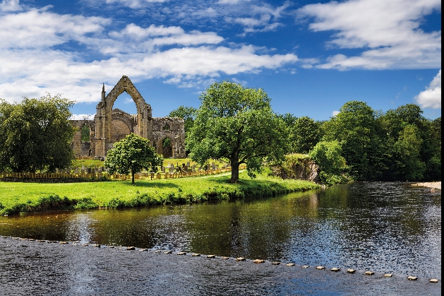 exterior of bolton abbey ruin with river in foreground