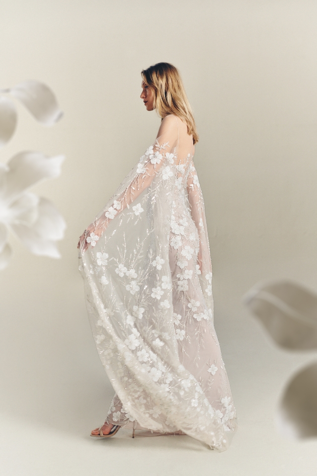 model in lace gown with large applique flowers and huge floor-length sleeves