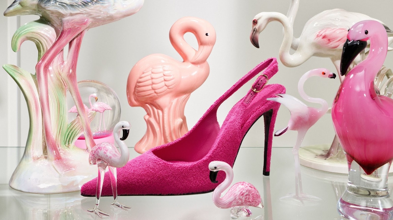 pink shoe on a table with lots of pink flamingos around it