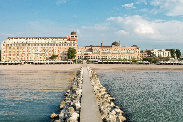 A stone path across the water with a large building in the background