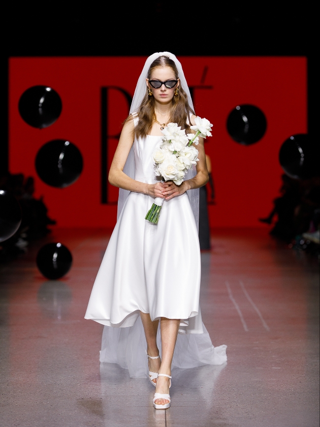 model in knee-length simple silk gown with veil and sunglasses on runway 