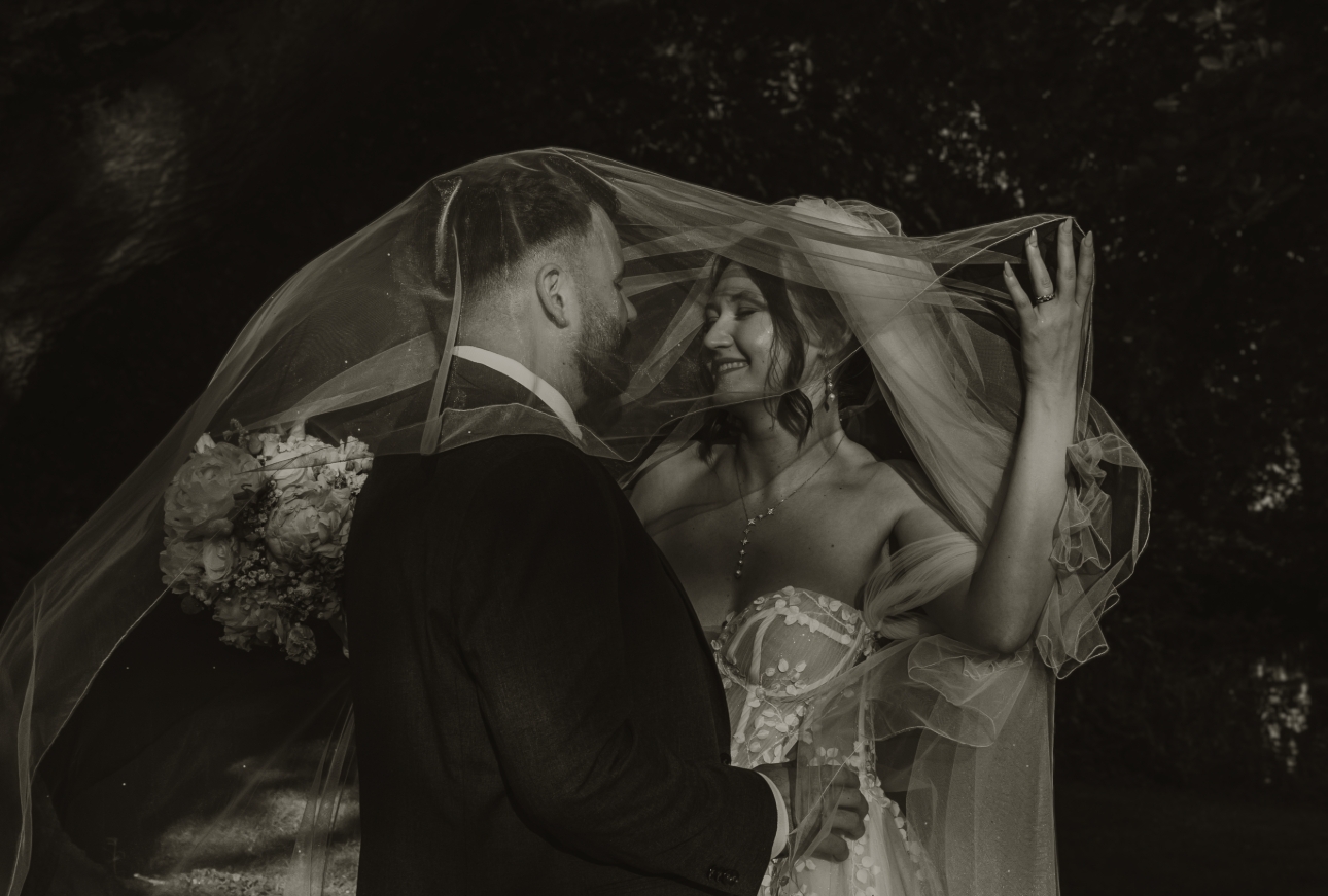 bride and groom posing under the bride's veil