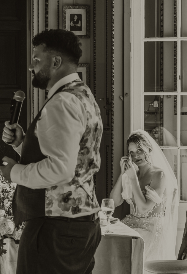 bride watching as groom gives speech