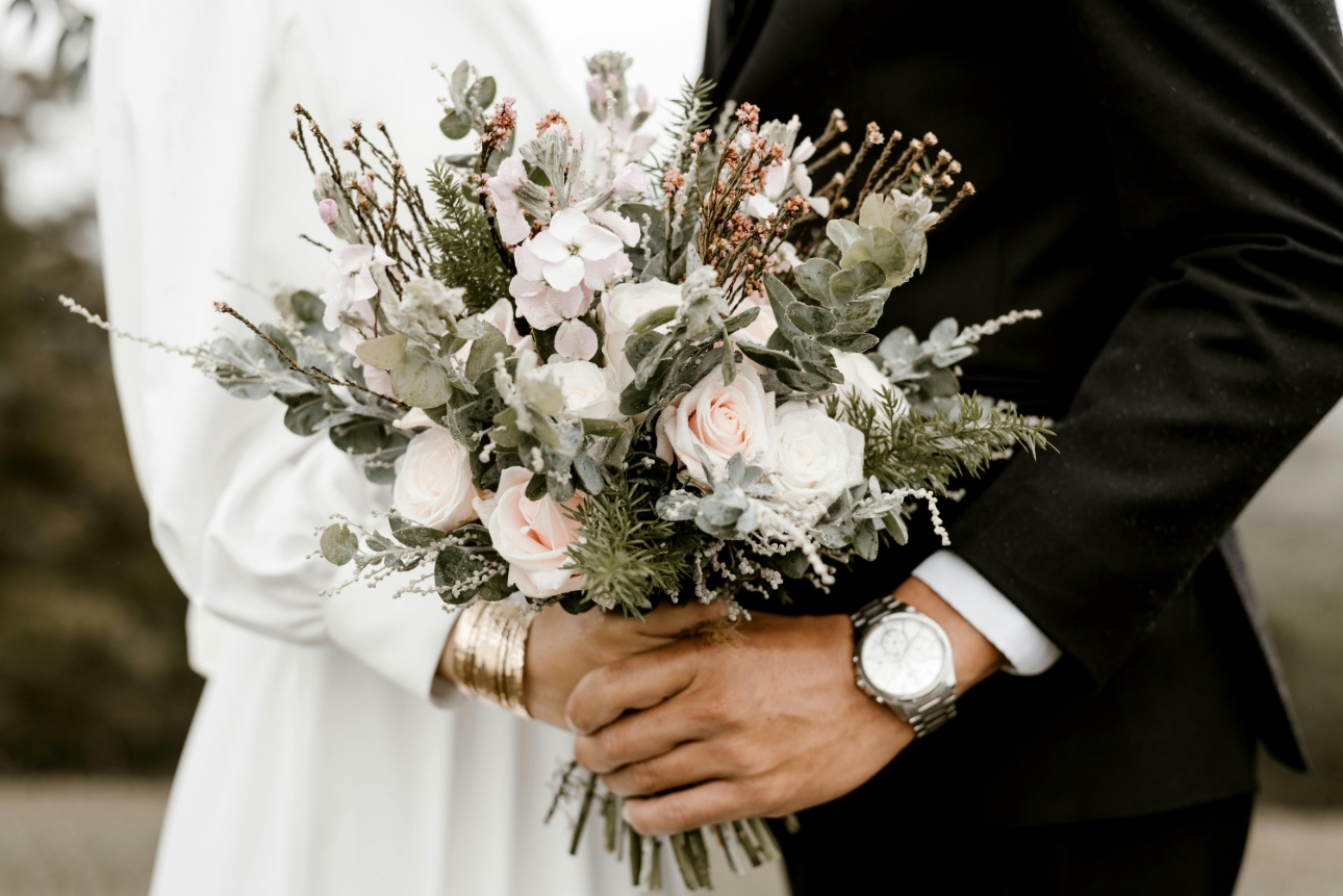 bride and groom image of holding bouquet shot from arm length 