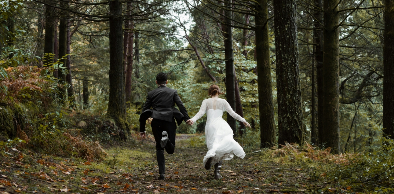 bride and groom running off in woods