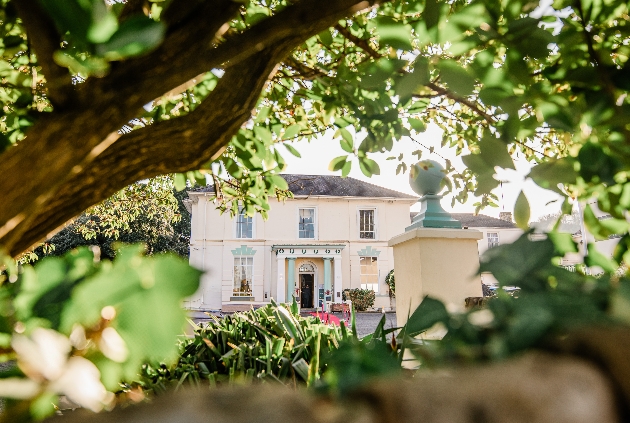 The exterior of.a large country house surrounded by trees