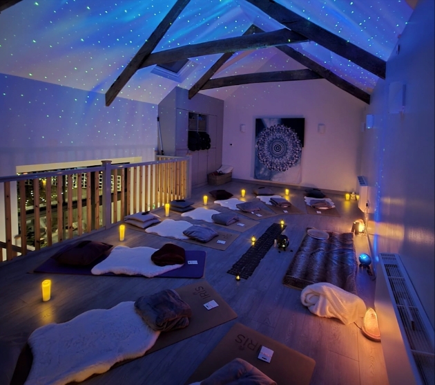 A room lit by candles with yoga mats rolled out