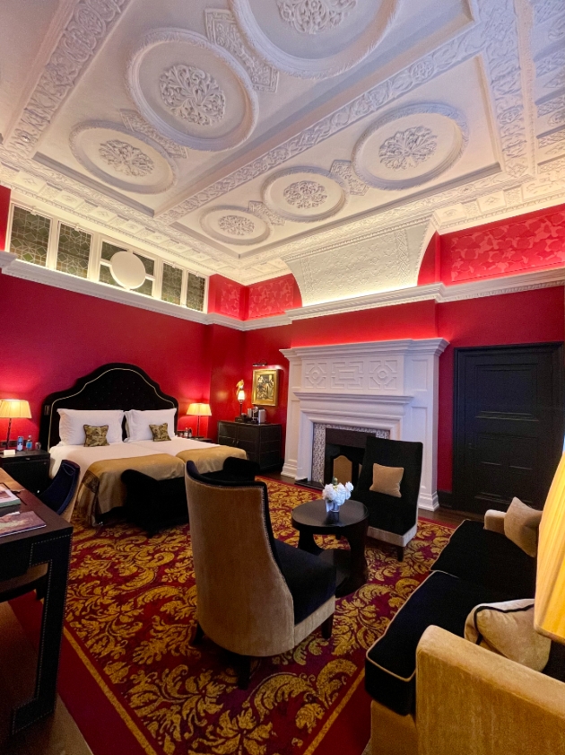 large bedroom suite with red walls white coving ceiling, plush baroque carpet